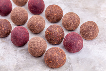 Obraz na płótnie Canvas Homemade Raw Vegan Cacao Energy Balls Lie in Row on White Marble Background. Healthy Chocolate Sweets from Nuts and Dates. Concept of Natural Vegetarian Handmade Dessert