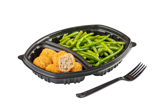 Breaded fried chicken nuggets and asparagus in plastic disposable tray with fork isolated on white background.