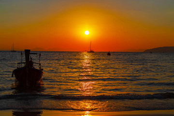 Fototapeta na wymiar Long tail boat sunset sky dusk golden hour clouds sun