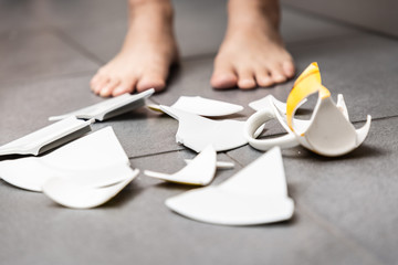 Picture of a child making a dish and a glass of water broken  on the kitchen floor. The concept is...