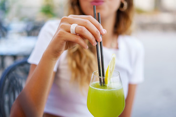 A girl is drinking a green juice with a straw. Young people who spend their evenings drinking in...