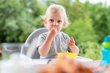 Focused and polite baby child eating lunch outdoor
