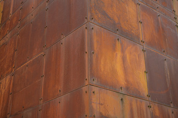 Corner section of a structure made from rusting steel plate.