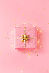 Pink gift with golden bow and decorative lights