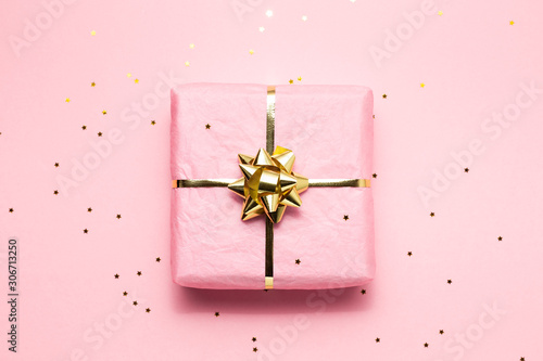 Pink and golden wrapped gift on pink background