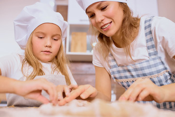 Obraz na płótnie Canvas family concept. young caucasian mother teaching her child girl to bake, to cook. Little kid girl help mother in kitchen