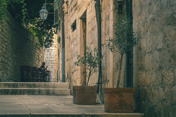 A silhouette of alone man sitting at the table of sidewalk cafe at the narrow street of an old town