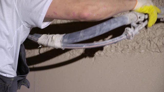 Plastering mortar machine. Automatic plaster. Repairing or renovating house or apartment. Builder at construction professional