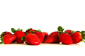 Bright red fresh ripe strawberries berries scattered and isolated on a white background