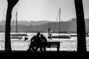 silhouette of a couple sitting on bench at sunset