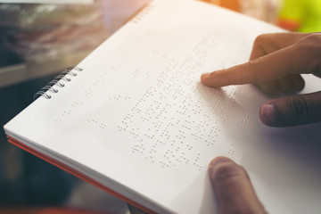 Close-up of fingers reading braille, Hand of a blind person reading some braille text of a braille book. - obrazy, fototapety, plakaty