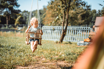 Little boy playing on swing in backyard at coutryside