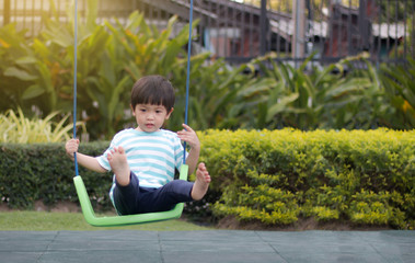 Young boy try to playing on a swing
