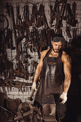 confident forger in leather uniform isolated in workshop. special equipment. strength and power concept. muscular body