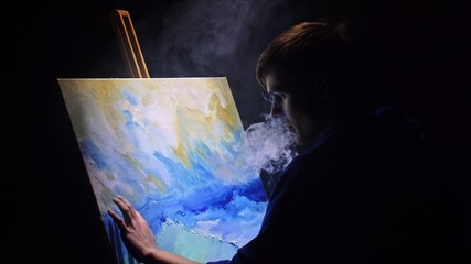 Artist copyist paint seascape with ship in ocean. Vaper smoke vape e-cigarette. Craftsman decorator draw as boat sail on blue sea with acrylic oil color. Draw finger, brush, knife palette. Indoor.