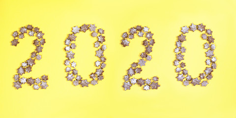 Concept Christmas layout 2020 lined with snowflakes gingerbread cookies sprinkled with icing sugar on a yellow background.
