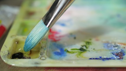 Fototapeta premium Artist copyist paint seascape with ship in ocean. Craftsman decorator draw as boat sail on blue sea with acrylic oil color. Draw finger, brush, knife palette. Indoor. Close up cinematic look.