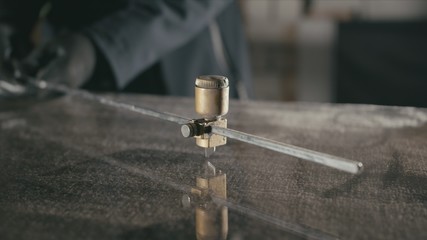 Forge. Smithy. Glass cutting and processing for fireplace doors. Circular glass cutter. Worker cut glass with glass cutting diamond. Polish an angle grinder with an abrasive circular disk nozzle.