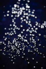 Abstract bokeh pattern of sparkling glass droplets on a dark blue background