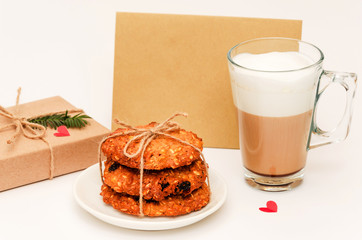 Valentine's day background. Homemade oatmeal cookies, transparent mug of cappuccino, gift box, blank card for congratulations, two small red hearts. Love and romantic relationships concept. Closeup