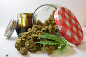 Dry and trimmed cannabis buds stored in a glas jars,a marijuana leave and a big BHO jar. Medical cannabis