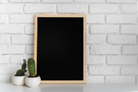 black mock up felt letter board with small succulents on white brick background