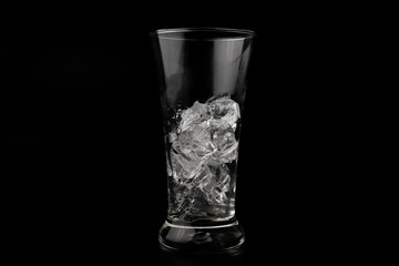 Glass with ice cubes on black background
