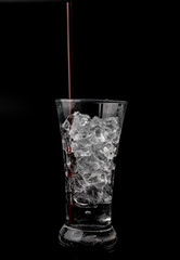 Glass with ice cubes on black background