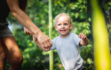 Obraz premium Little child with his mom playing on trampoline outdoor in backyard