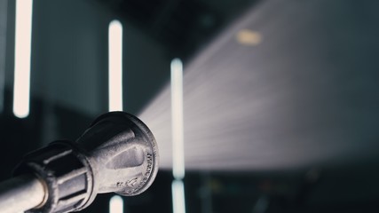 Water hose car washing close up. Worker man watering with foam auto out of manually high pressure...