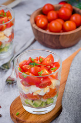  Portion salad with smoked salmon, avocado, egg, cherry tomatoes with cream cheese dressing in a glass. Holiday salad for Christmas and New Year.