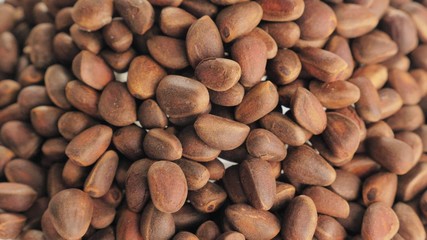 Pine nut rotate are on a table in a plate. Snack in transparent dish on an isolated white background are spinning moving. Delicious and healthy protein-rich diet food.