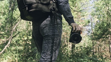 Traveler photographing scenic view in forest. One caucasian woman shooting close up look. Girl hold dslr mirrorless camera in his hand. Professional photographer travel with backpack. Outdoor.