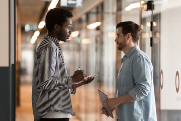Multi-ethnic colleagues standing in office hallway and talking