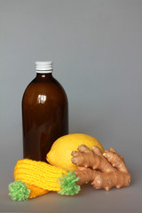 syrup in a bottle of dark glass with lemon and ginger on a gray background