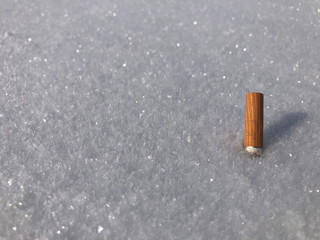 cigarette butt, yellow and white, thrown into fresh snow on a sunny day, garbage, dirt, pollution, mountain, alps, winter, environment