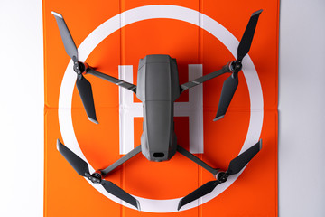 Drone standing on orange helicopter landing pad mat. Drones and technology concept.