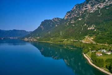 Fototapeta na wymiar Panoramic view of the mountains and Lake Idro-Lago d'Idro. Autumn season, the reflection in the water of the mountains, trees, blue sky