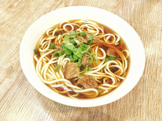 A bowl of California beef noodles sits on a board