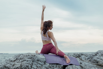 Girl exercising, yoga sitting on a foggy mat, an amazing yoga landscape with mountain views in the morning mist. Health care exercise concepts