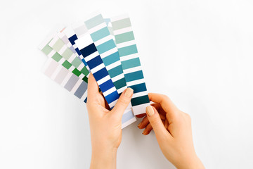 Female hand holding color swatches. Color trend palette. Flat lay, top view.
