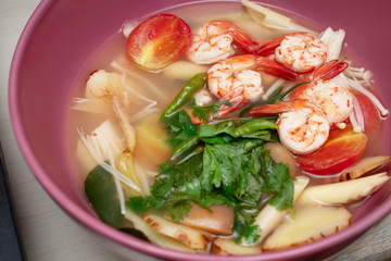 Tom Yum Goong, spicy shrimps and seafood soup with variety of herbs in pink big bowl, Popular hot and sour Thai traditional soup