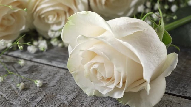 White roses on a rustic wood table top.