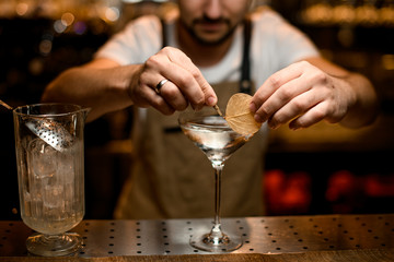 Bartender pins dry leaf to a cocktail