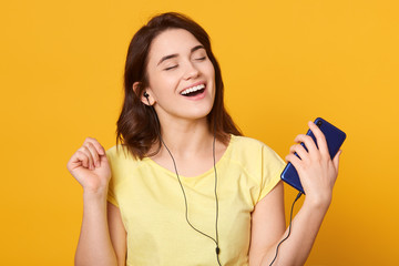Woman dancing and listening to music in headphones from smart phone or mp3 player, happy Caucasian...