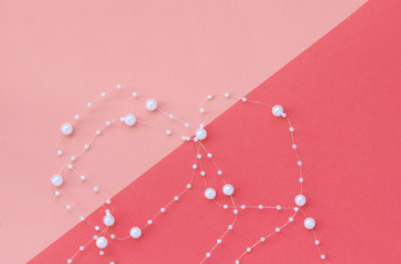 Holiday composition. White beads on a pink background, diagonal. Holiday, Valentine, Christmas, New Year concept. Top view, flat lay, place for text.