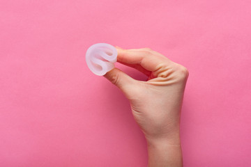 Close up view of woman holding menstrual cup isolated over rose background, woman's period, menstrual cup in hands, modern methods for crytical days. Gynecology and hygiene products concept.