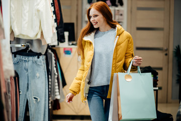 beautiful redhaired woman in yellow coat want to buy new outfit, in search, looking for dress