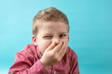 boy covered his nose with his hand. smells bad. frowns from the bad smell - obrazy, fototapety, plakaty
