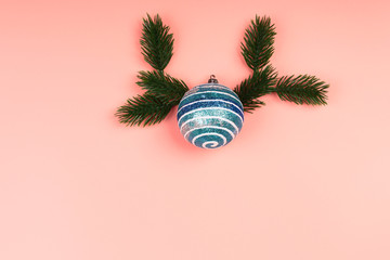 Christmas layout blue glitter Christmas ball with spruce branches on a pink background. Place for text, flat style, top view. Minimalistic Scandinavian style.